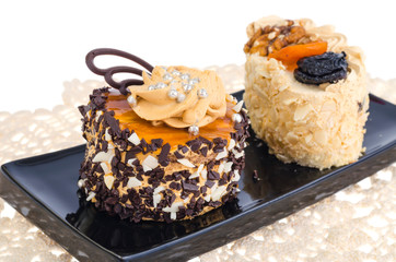 Two delicious sweet cream cakes on black plate.
