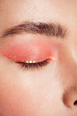 Naklejka premium cropped view of woman with coral glitter makeup and eyes closed