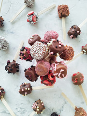 Dessert in chocolate (ice cream, cake pop, banana) on a stick, decorated with berries, coconut and chocolate chips