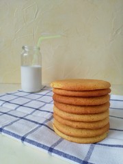 a stack of round cookies on the background of a glass of milk and towels