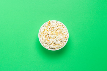 Bowl with popcorn on a green background. Flat lay, top view.