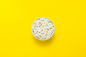 Bowl with popcorn on a yellow background. Flat lay, top view.