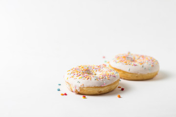 Fresh tasty donuts and sweet multicolored decorative candy on a white background. Bakery concept, fresh pastries, delicious breakfast.