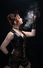 A beautiful redhead cosplayer girl wearing a Victorian-style steampunk costume with big breasts in a deep neckline holds her hand in a puff of smoke on a black background