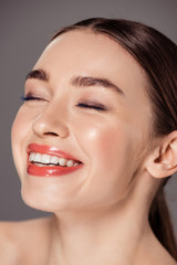 Obraz premium portrait of beautiful smiling girl with eyes closed isolated on grey