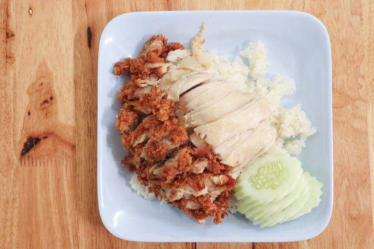 Hainanese chicken rice with Roasted Chicken on wooden table.Hainanese chicken rice is a dish of poached chicken and seasoned rice, served with chili sauce