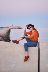 Young stylish girl sitting at a sea port