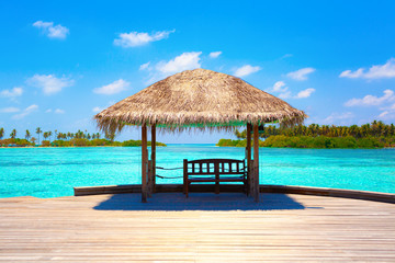 summer hot caribbean maldives vacation beach background - view on the azure blue tropical exotic sea with wood bridge and loungers and house on island with palms pier