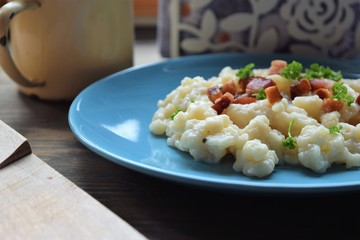 Slovak traditional potato gnocchi with sheep cheese and bacon,wooden table