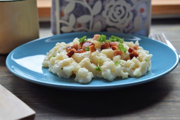 Slovak traditional potato gnocchi with sheep cheese and bacon,wooden table
