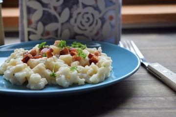 Slovak traditional potato gnocchi with sheep cheese and bacon,wooden table