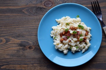 Slovak traditional potato gnocchi with sheep cheese and bacon,wooden table