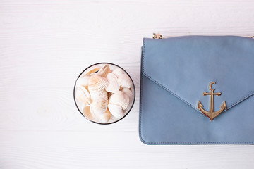 Seashell on wooden background. Sea concept. Blue cross body bag on light background