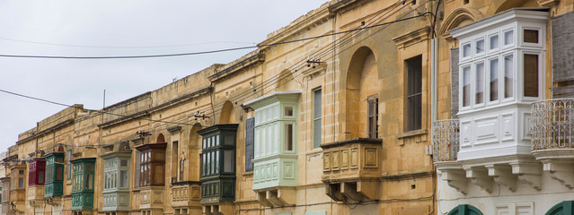 Fototapeta na wymiar Traditional, wooden balcony and stone facade, typical for architecture of Gozo, Malta