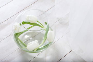 Fresh white tulips in a spherical glass vase. Closeup image