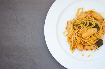 Spaghetti with sausage, Stir-fried sausage, Italian food.Spaghetti with red sauce, white plate on the table in the morning restaurant.