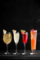 different cocktails in glasses of different shapes on black background