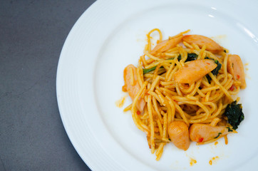 Spaghetti with sausage, Stir-fried sausage, Italian food.Spaghetti with red sauce, white plate on the table in the morning restaurant.