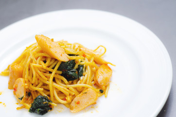 Spaghetti with sausage, Stir-fried sausage, Italian food.Spaghetti with red sauce, white plate on the table in the morning restaurant.
