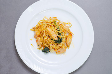 Spaghetti with sausage, Stir-fried sausage, Italian food.Spaghetti with red sauce, white plate on the table in the morning restaurant.