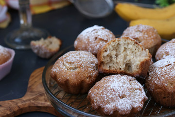 Muffins with bananas are located on plates against a dark background