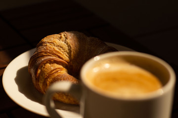 A fall breakfast with coffee, capuccino and a big french croissant