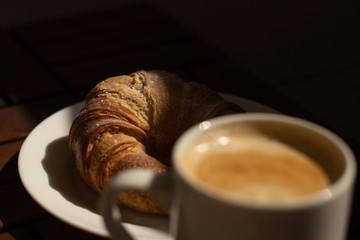 A fall breakfast with coffee, capuccino and a big french croissant