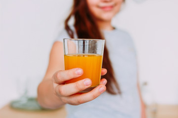 The girl holding glass of orange juice in hand, selective focus