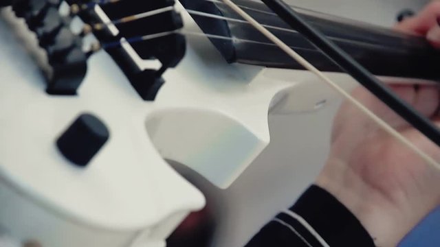 close view modern white violin in hands of talented woman musician playing melody in orchestra at concert
