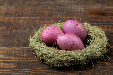 Fototapeta na wymiar Easter. Pink easter eggs in a nest on a brown wooden table. Happy easter. holidays