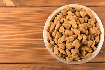 Bowl with dog food on a wooden table. Close up.