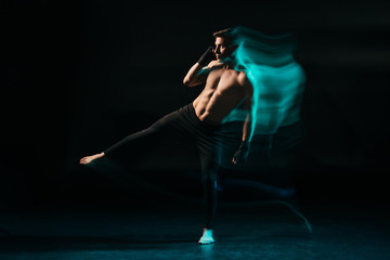 Long exposure of green light and shirtless muscular mma fighter raising leg