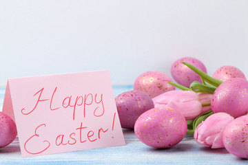 Easter. Pink easter eggs and flowers tulips on a blue wooden table. Happy easter. holidays.