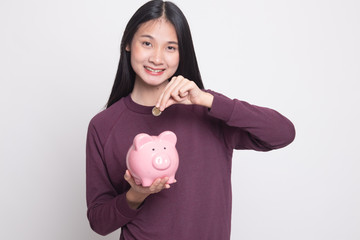 Asian woman with coin and pig coin bank.