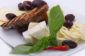  Cheese plate - four types of cheese with plums, red pepper and toast. Snacks on a white plate. On a white background