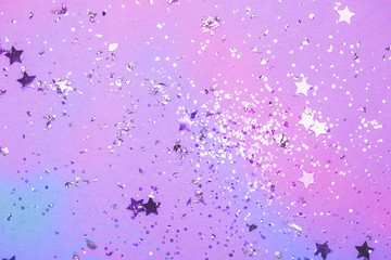Violet confetti and stars and sparkles on pink background. Top view, flat lay. Copyspace for text. Bright and festive holiday background. Neon colors. Waporwave style