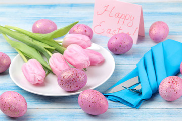 Easter. Easter table setting. Pink easter eggs and flowers tulips on a blue wooden table. Happy easter. holidays.