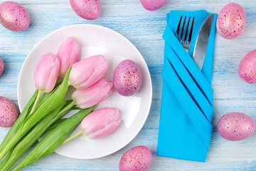 Easter. Easter table setting. Pink easter eggs and flowers tulips on a blue wooden table. Happy easter. holidays. top view.