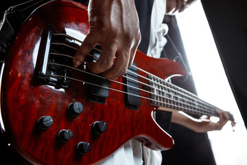 African American handsome jazz musician playing bass guitar in the studio on a black background....