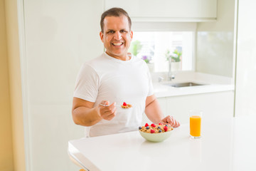 Handsome middle age senior man eating healthy cereals for breakfast in the morning