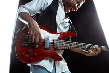 African American handsome jazz musician playing bass guitar in the studio on a black background....