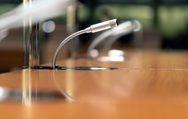 Mikrofone auf einem Tisch in einem Konferenzsaal – selektiver Fokus, sehr wenig Tiefenschärfe...