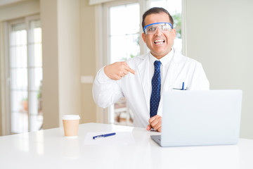Fototapeta premium Middle age scientist man wearing professional glasses working using laptop with surprise face pointing finger to himself