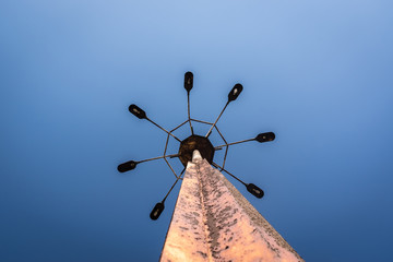 Big old rusty lighting 8 way on the pole under blue sky