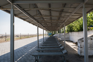 Old rusty sun canopy with sun loungers and lanterns on the sea promenade