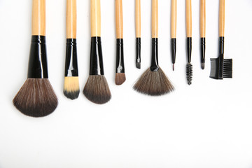 makeup brushes of different shapes and sizes. cosmetic accessories on white background. background...