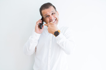 Middle age man calling using smartphone very happy pointing with hand and finger