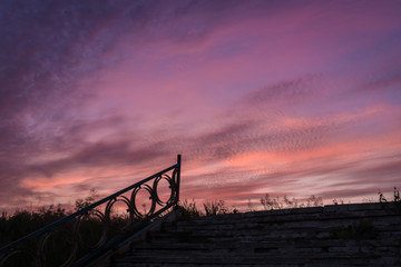 Old park staircase with an openwork fence on the background of a beautiful sunset