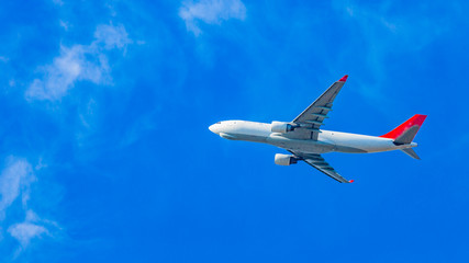 White commercial airplane flying over a clear blue sky on a sunny day in the Netherlands