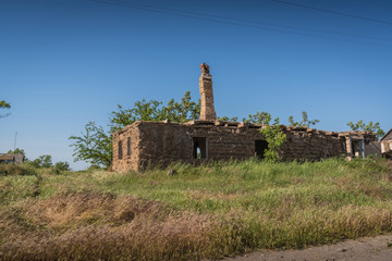 Abandoned ruined house with chimney on blue sky background